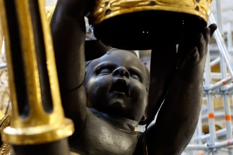 A statue of a cherub holding the papal tiara.