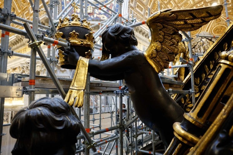 A statue of a cherub holding the papal tiara.
