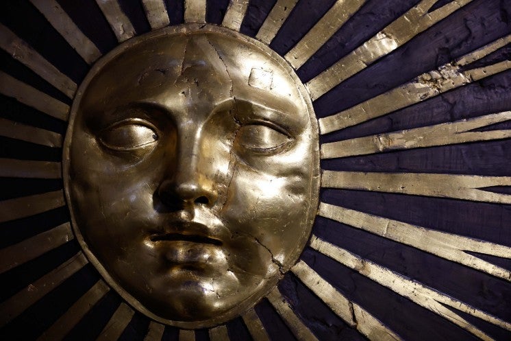 A face depicted as a golden sun decorating a column.