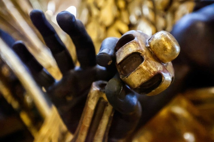 A statue of an angel holds a golden ornament.