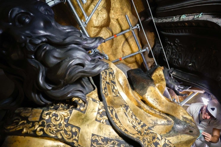 A restoration professional cleans a statue.