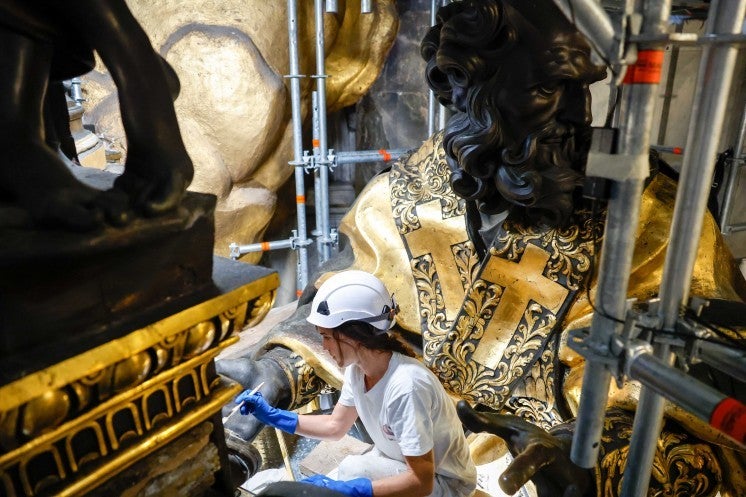 A restoration professional cleans a statue.