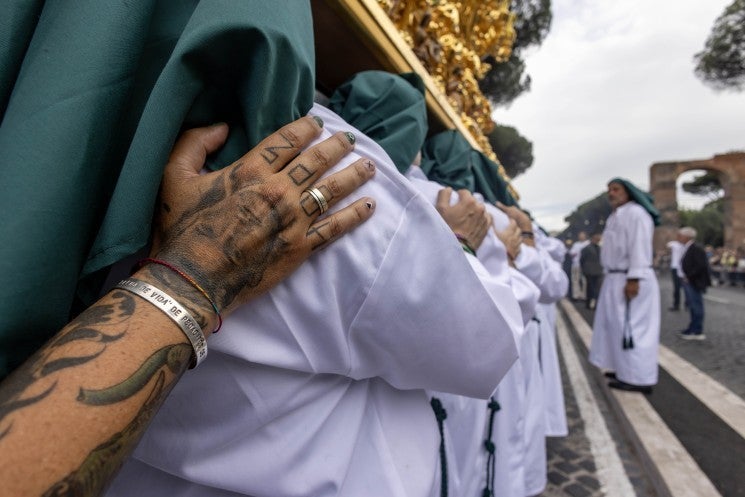 Man with tattoo helps carry statue of Mary